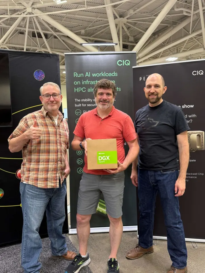 An attendee holding an NVIDIA DGX Spark box between two CIQ team members
